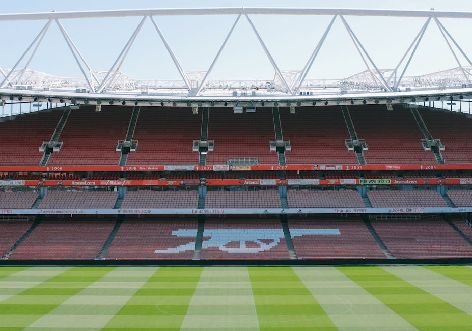Photograph of an empty seating area inside Twickenham Stadium, showing rows of red plastic seats arranged in a curved pattern on an indoor tiered balcony. The seats are clean but some show signs of we